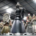SpaceX Raptor 3 engine standing in front of a row of Raptor 2 engines in a factory
