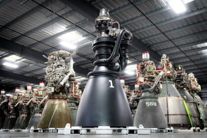 SpaceX Raptor 3 engine standing in front of a row of Raptor 2 engines in a factory