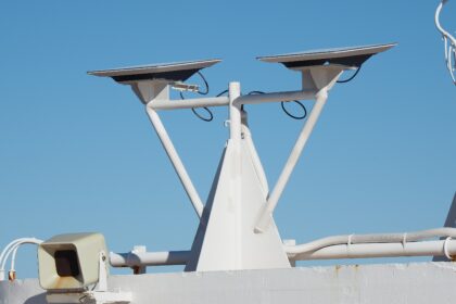 Two Starlink flat-panel dishes mounted on a white pole against a blue sky