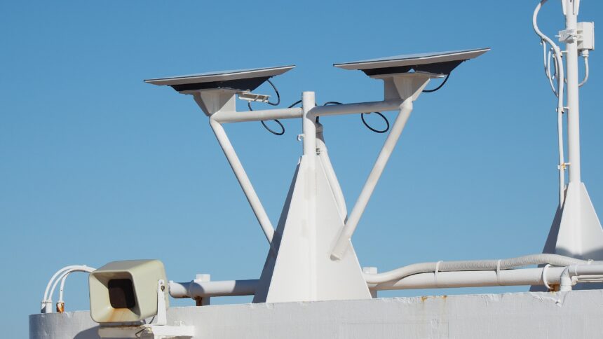 Two Starlink flat-panel dishes mounted on a white pole against a blue sky